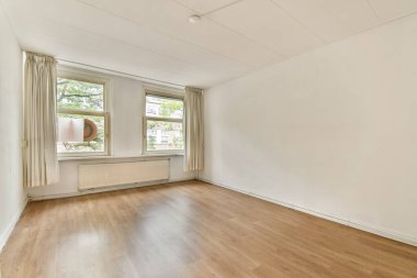 Geniş, güneşli, geniş pencereli ve nötr duvarlı bir oda. Basit tasarım minimalist estetiği vurgular. Modern yaşam için mükemmel..