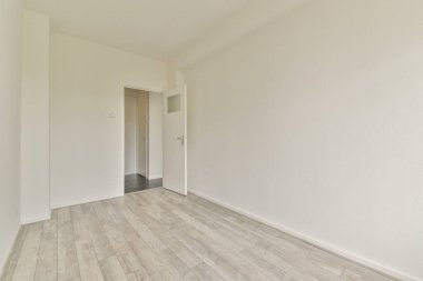 Geniş, modern bir oda. Açık ahşap döşemeleri ve beyaz duvarları olan temiz, minimalist bir tasarımı var. Parlak ve havadar bir atmosferi var..