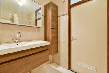 Zarif ve işlevsel banyo. Parlak bir lavabo, ahşap dolap ve estetiği geliştiren büyük bir ayna..