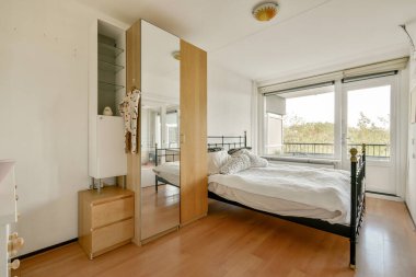 Huzurlu ve minimalist bir yatak odası, rahat bir yatak odası, büyük pencerelerden gelen doğal ışık, ve rahatlama ve sükuneti teşvik eden basit bir dekor..