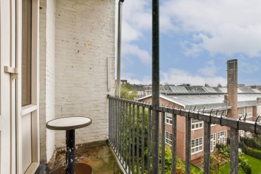 Huzurlu bir balkon manzarası modern mimari, yeşillik ve bulutlu gökyüzünün bir karışımını sergiliyor, kentsel sükunet ve doğanın dokunuşunu kapsıyor.