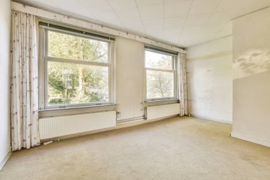 Açık renkli duvarlar ve düz bir halı ile tamamlanmış doğal ışığa izin veren geniş pencereli bir hava odası. Rahat bir ortam yaratmak için mükemmel..