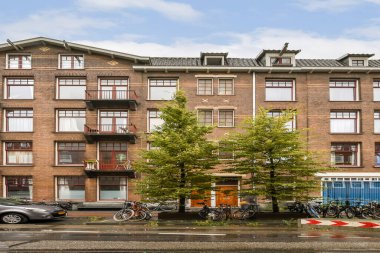 Estetik açıdan memnun edici modern bir apartman balkonları ve kentsel çevrede bulunan yemyeşil ağaçlar park halindeki bisikletlerle tamamlanmış..