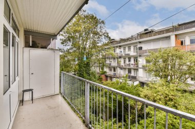 Parlak, modern bir balkon, yemyeşil ağaçlara ve komşu binalara bakıyor. Huzurlu bir şehir manzarası yaratıyor. Rahatlamak ve eğlenmek için mükemmel..