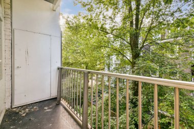 Sakinleştirici bir balkon manzarası canlı yeşil ağaçlar ve yeşillikler sergiliyor, rahatlatıcı bir davet ve doğayla bir bağ..
