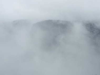 Yoğun sisten zar zor görünen dağların gizemli ve ruhani görüntüsü sisin içinde dingin ve dünyevi bir atmosfer yaratıyor.