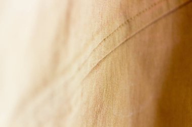 Close-up of tan fabric from an off-shoulder blouse, focusing on stitching and fabric texture clipart