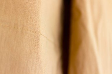 Omzunun dışındaki bir bluzun bronz kumaşı, dikişleri ve kumaş dokusunu vurguluyor.