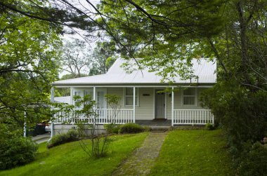 Leura, Blue Mountains, Avustralya 'da teneke çatılı klasik bir beyaz kulübe. Beyaz bir korkuluk, kaldırım taşı yolu ve canlı yeşil çimenler var..