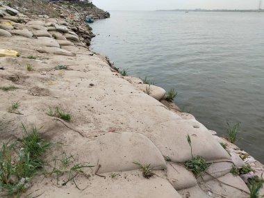 Kum torbalarıyla Ganga nehri. Tortuyla ilgili felaketler için kum torbaları. Esnek bir torbaya kum koy. Toplu bir torbaya kum koy.