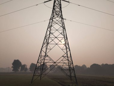 Yüksek Gerilim Elektrik Kulesi 'ne bakan Tarım Alanı' nda sabah. Elektrik konsepti, yüksek voltajlı elektrik hatları istasyonunu kapatın. Yüksek voltajlı elektrik iletim pilonu siluetli kule.