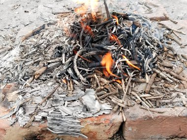 Sarı ve turuncu renkli ateşli alevlerle izole edilmiş güzel bir şenlik ateşi. Kış mevsiminde çevreyi sıcak tutmak için yakılacak odunların eksik yanmasını tasvir ediyor..