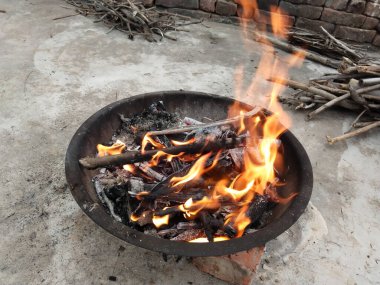 Sarı ve turuncu renkli ateşli alevlerle izole edilmiş güzel bir şenlik ateşi. Kış mevsiminde çevreyi sıcak tutmak için yakılacak odunların eksik yanmasını tasvir ediyor..