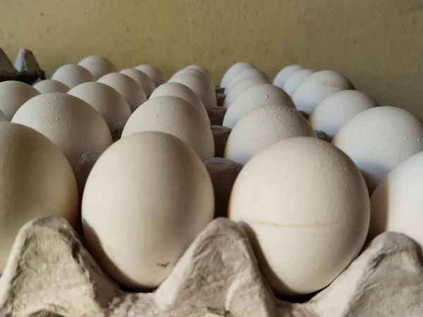 マーケットストールで販売するトレイに新鮮な白いアヒルの卵の層に積まれて 調理のための台所の茶色の紙パネルの卵の山 — ストック写真