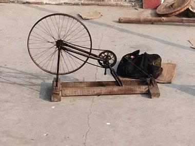 Varanasi, Hindistan 'daki köyde Charkha' ya iplik bağlayan el dokuma makinesi. Dokumacı el dokumasıyla kumaş yapmak için iplikler hazırlar, eski moda dönen bir tekerlekte iplik çevirir..