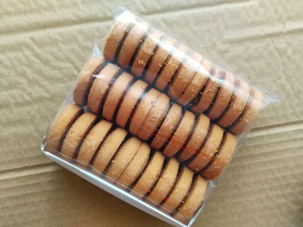 Packing cookies on a brown background. Biscuits in plastic packaging. copy space, place your text