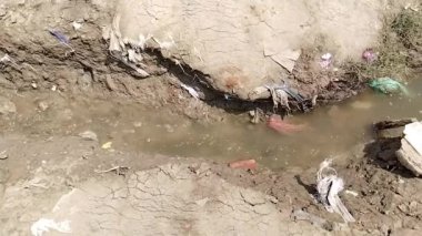 Nehir suyuna akan küçük bir hendekte akan sulama suyu manzarası. Kumda akan su, küçük kirli hendek nehri 