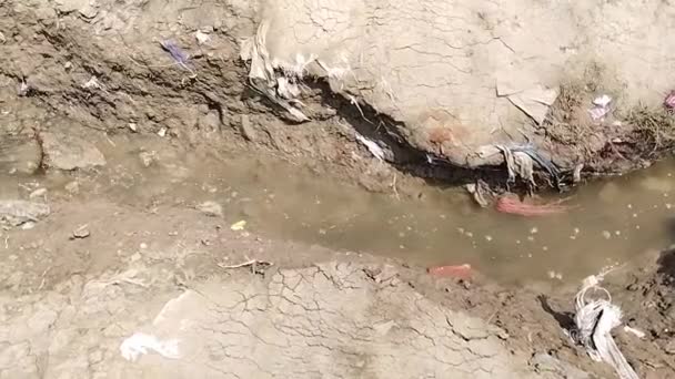 小さな溝から川水に流れる灌漑水の眺め 砂に流れる水 汚れた小さな溝の川 — ストック動画