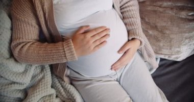Close up pregnant woman making heart shape with her hands on her belly while toughing it tenderly . High quality 4k footage