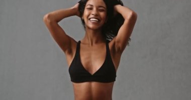 Lovely Mixed race woman sitting laughing smiling while playing with hair in her swimwear