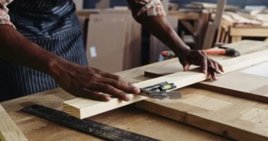 African carpenter carefully measuring his plank of wood for his carpentry project. High quality 4k footage