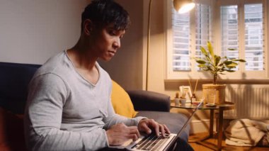 Close up Asian man very seriously typing on his laptop on his sofa . High quality 4k footage