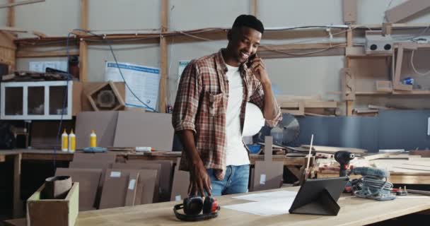 工場で働くデザインを議論する携帯電話の若いアフリカ人男性 高品質4K映像 — ストック動画