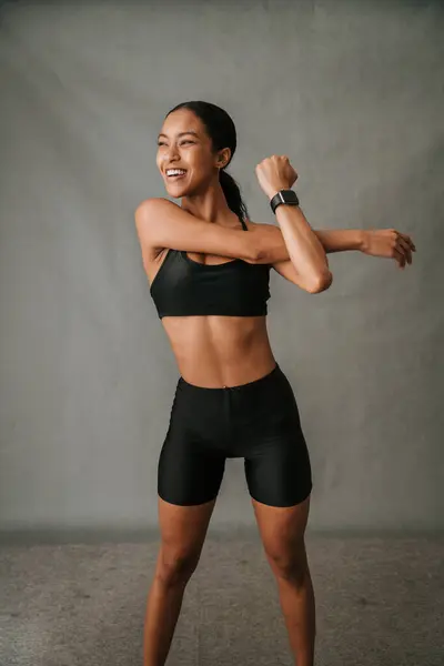 Afro-Amerikan gülümseyen bir kadın. Saati yerinde duruyor ve stüdyoda kol esnetme egzersizi yapıyor. Yüksek kalite fotoğraf