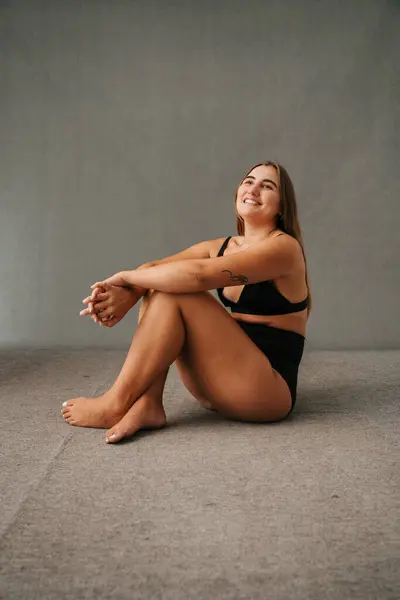 Fun-loving female in her active wear sitting on the studio floor waiting to start work out . High quality photo