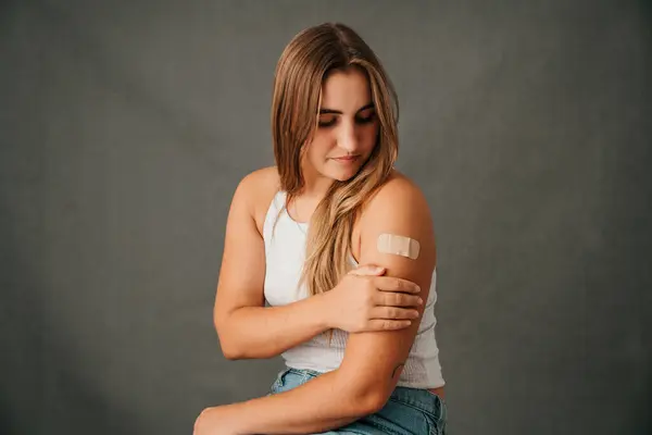 Ung Allvarlig Vit Kvinna Tittar Hennes Plåster Armen Och Vidrör — Stockfoto