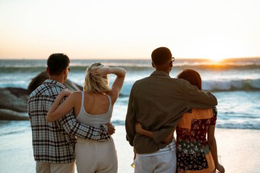 Gün batımında birbirini kollayan iki çift denizi seyrediyor. Yüksek kalite fotoğraf
