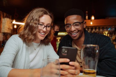 Çeşitli arkadaşlar akşam yemeği için hücresel cihazdan selfie izleyip biranın tadını çıkarıyorlar. Yüksek kalite fotoğraf