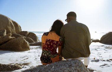 Bir kadın sahildeki erkek arkadaşının üzerinde başını dinlendiriyor. Gün batımı. Yüksek kalite fotoğraf