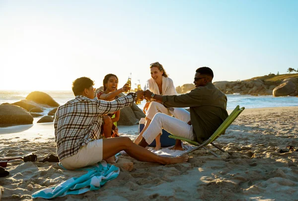 Four people toasting at the beach during sunset. Four friends on the beach. Sundowners. High quality photo