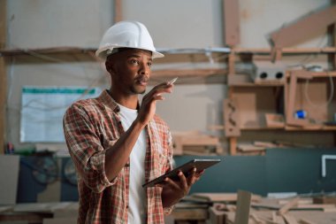 Afrikalı erkek, marangozluk fabrikasındaki stokları kontrol etmek için tablet kullanıyor. Yüksek kalite fotoğraf
