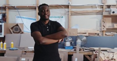 Katlanmış kolları olan mutlu Afrikalı erkek atölyede fotoğraf için poz veriyor. Yüksek kalite 4k görüntü