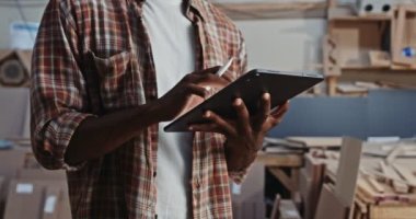Marangozluk atölyesinde Afrikalı bir erkeğin tablet kullandığı yakın çekim. Yüksek kalite 4k görüntü