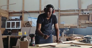 Genç odaklı Afrikalı marangoz, fabrikasındaki ahşap iş projesinde delik açmaya çalışıyor. Yüksek kalite 4k görüntü