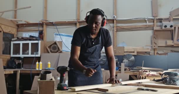 Fiatal Fókuszált Afrikai Asztalos Füldugóval Fúrt Lyukakat Fából Készült Munkáiban — Stock videók