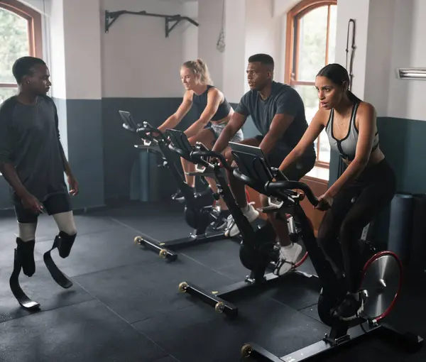 A group of individuals are participating in indoor cycling on stationary bicycles as part of a circuit training