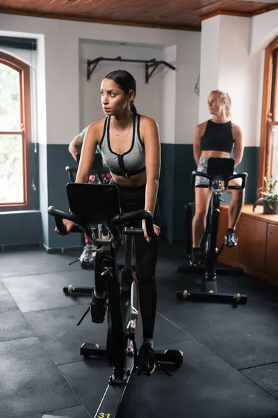 Två Kvinnor Trampar Motionscyklar Gymmet Tränar Låren Och Bygger Uthållighet Royaltyfria Stockbilder