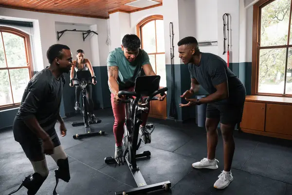 남자의 그룹은 체육관에서 자전거에 여유롭게 운동을 즐기고 배경에서 스포츠 장비와 로열티 프리 스톡 사진