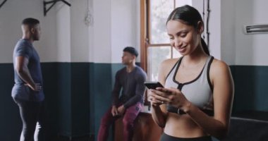 Çok ırklı genç bir kadın fitness stüdyosunda telefona gülümsüyor. Yüksek kalite 4k görüntü