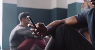 Fitness stüdyosunda cep telefonuyla kayan Afrikalı bir sporcunun orta boy fotoğrafı. Yüksek kalite 4k görüntü