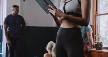 Genç bir kadın antrenmandan önce spor salonunda tablet kullanıyor. Yüksek kalite 4k görüntü