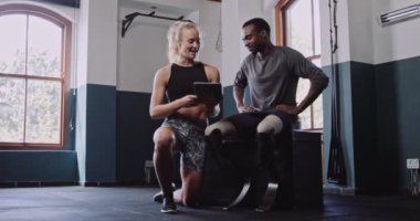 Genç Afrikalı çift bacak protezli bir erkek kapalı spor salonunda kadın antrenörle konuşuyor. Yüksek kalite 4k görüntü.