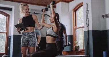 Spor salonunda ağırlık çalışırken, antrenör formda bir kadına yardım ediyor. Yüksek kalite 4k görüntü