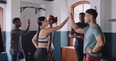 Birlikte antrenman yaptıktan sonra kapalı bir spor salonunda kutlama yapan ve beşlik çakan sağlıklı ve çeşitli bir arkadaş grubu. Yüksek kalite 4k görüntü.