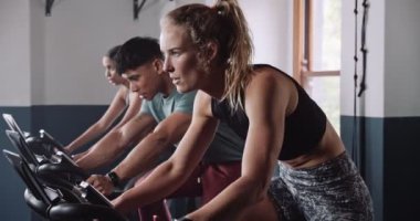 Spor kıyafetleri içinde kolsuz tişörtler ve şortlar da dahil olmak üzere bir grup insan spor salonunda birlikte çalışıyor. Video onların yoldaşlık ve uygunluk rutinlerini yakalıyor.