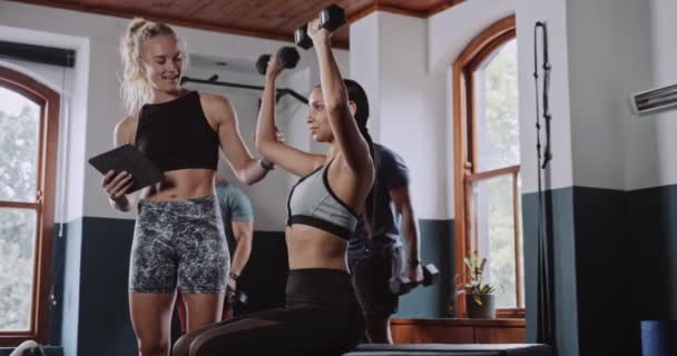 教练帮助合适的女人在健身房练举重 高质量的4K镜头 — 图库视频影像